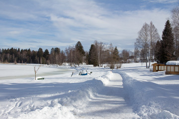 A path leads through deep snow into a forest