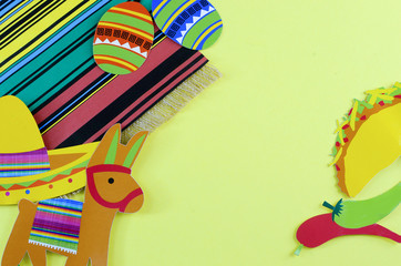 Cinco de Mayo image with copy space on yellow background surrounded by colorful party props with Mexican themed subjects