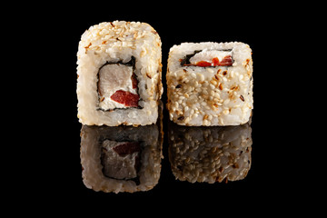 Concept of Asian cuisine. Two rolls of sushi with different fillings on a black background with the age for a Japanese menu for a cafe, restaurant, sushi bar.
