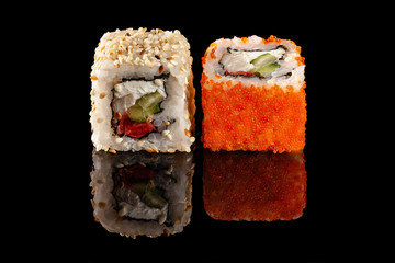 Concept of Asian cuisine. Two rolls of sushi with different fillings on a black background with the age for a Japanese menu for a cafe, restaurant, sushi bar.