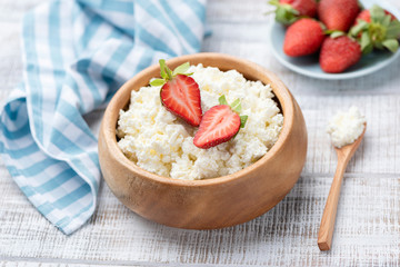 Tvorog, curd cheese or cottage cheese in wooden bowl. Old white rustic wooden table background. Healthy eating, healthy food concept