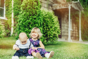 Summer happy time. Two cheerful infant babies outdoors smiling and playing together in green sunny park. Childhood, happiness, infant baby concept