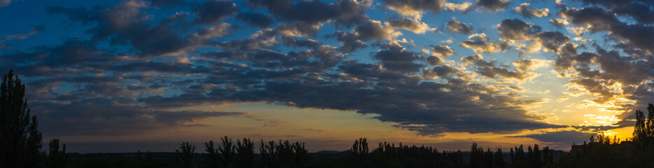 Landscape with dramatic light - beautiful golden sunset with saturated sky and clouds.