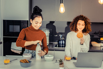 Curly red-haired woman eating tasty cookie sitting near her friend