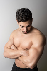 Latin fit man poses serious in studio shot showing his torso
