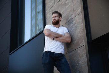 Fototapeta premium young bearded man crossed her arms over his chest against of office building