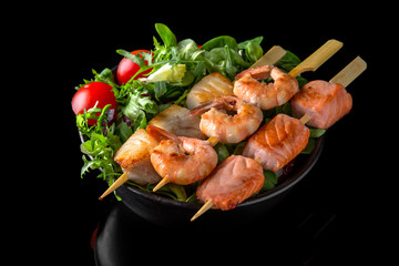 Nutritious dietary salmon and shrimp with salad of green mix: arugula, valerian, lettuce, Chinese cabbage and tomatoes on black background