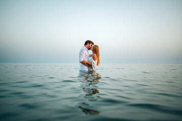 Two lovers on the beach kissing and hugging in the hot summer sun on a sandy beach