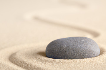 Zen meditation stone with raked line in sand. Concept for harmony relaxation and purity. Spa wellness background