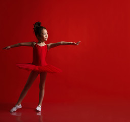 Cute little girl ballerina in beautiful dress is dancing on red 