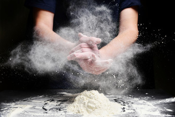 Cook slams splash hands with flour. White dust cloud of flour