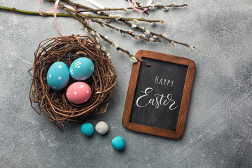 Blue and pink colored eggs in nest and pussy willow. Easter greeting card. Top view with space for your greetings