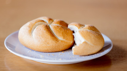 Kaiser roll on a plate on wooden table