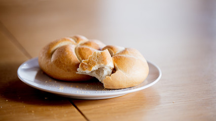 Kaiser roll on a plate on wooden table