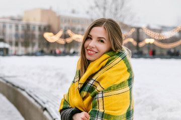 Beautiful girl in a warm yellow scarf walks in the winter city. Weekend in February