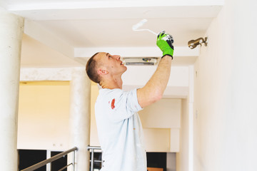 Man using Paint roller to paint the walls. Professional Wall decorating, interior renovation