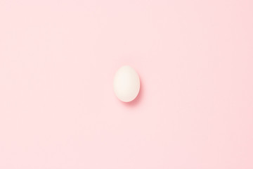 White egg on a pink background. The concept of life insurance, health and property, waiting for the birth of a child. Minimalism. Flat lay, top view