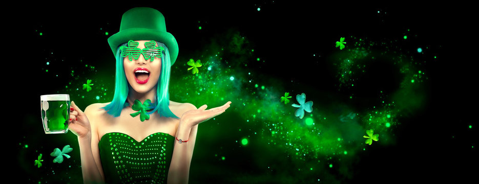 St. Patrick's Day. Leprechaun model girl with pint of green beer over dark green background, decorated with shamrock leaves. Patrick Day celebration