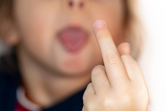 Small naughty child on white background is showing middle finger and tongue, impolite and rude fuck off expression