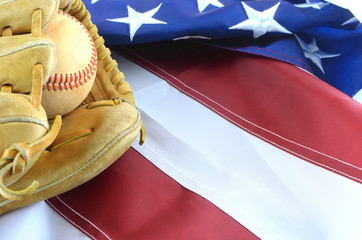 Closeup of worn baseball and mitt on a US flag background, great for America's favorite pasttime. Copy space. 