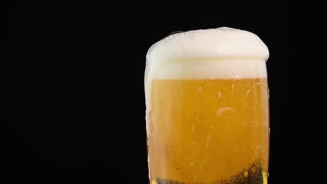 Close up pouring lager beer in glass over black