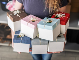 Workshop: The girl is holding a lot of multi-colored gift boxes and ribbons.