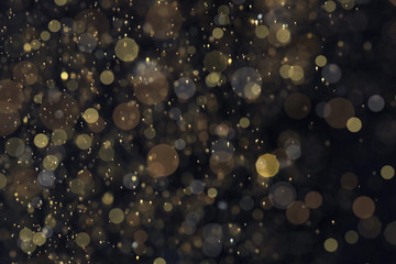 Golden glitter with bokeh effect on dark background