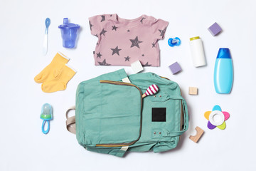 Composition with maternity backpack and baby accessories on white background, top view