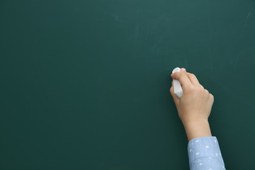 Little child writing on chalkboard, closeup. Space for text