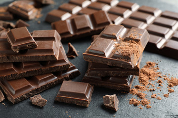Pieces of tasty chocolate on slate plate, closeup