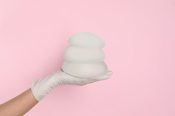 Doctor holding silicone implants for breast augmentation on color background, space for text....