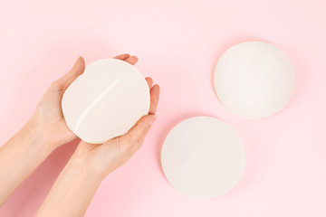 Woman holding silicone implant for breast augmentation on color background, top view. Cosmetic...