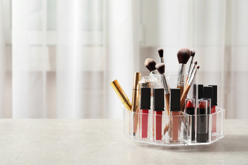 Lipstick holder with different makeup products on table indoors. Space for text