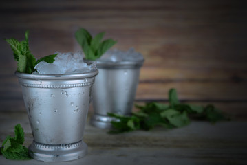 Image for Kentucky Derby in May showing two silver mint julep cups with crushed ice and fresh mint...