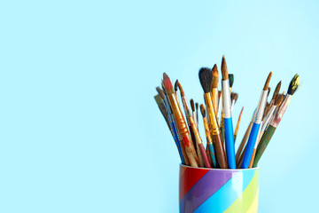 Fototapeta premium Holder with paint brushes on color background. Space for text