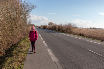 Girl walking on the shoulder of a road