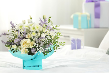 Beautiful bouquet of flowers in decorative crate on bed. Space for text