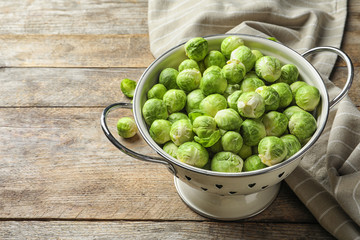 Colander with Brussels sprouts and cloth on wooden background. Space for text