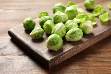Board with Brussels sprouts on wooden table, closeup