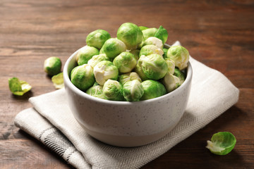 Bowl of fresh Brussels sprouts and napkin on wooden table