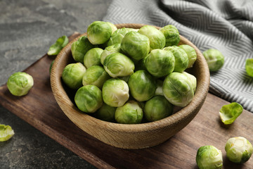 Board with bowl of Brussels sprouts on grey table