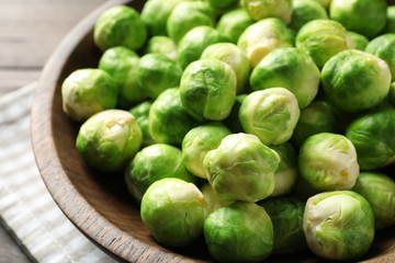 Fresh Brussels sprouts in bowl on table, closeup