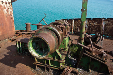 Old rusty winch mechanism in old rusty wrecked ship on sea shore
