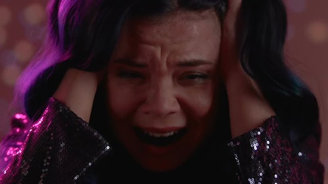 Frightened woman screaming in night club, drug influence, mental disorder