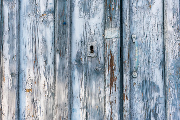Dilapidated blue wood barn doors with lock and handle