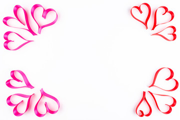 Hearts made from pink and red, satin ribbon on white background with clipping path and copy space in the middle, view from the top. Valentines Day concept.