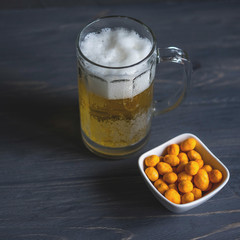 Photo of a glass of beer with nuts. Light beer on a dark background