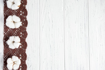 Wooden white background with cotton flowers, natural dried leaves of a bush and a cap. Winter concept with natural cotton flowers and a place for copispeys