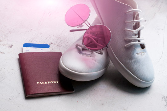 Russian passport with a boarding pass for the plane, white sports shoes and pink sunglasses. Travel concept Selective focus.
