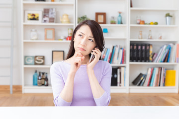 部屋で電話をする女性　考える